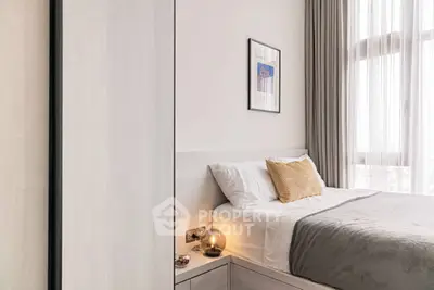 Modern bedroom with stylish decor and natural light, featuring a cozy bed and elegant curtains.
