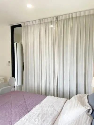 Modern bedroom with elegant curtains and cozy bedding in a stylish apartment.