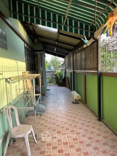 Charming covered patio with tiled flooring and green walls, perfect for relaxing outdoors.