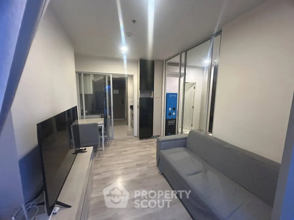 Modern living room with sleek design and open layout, featuring a cozy sofa and large TV.