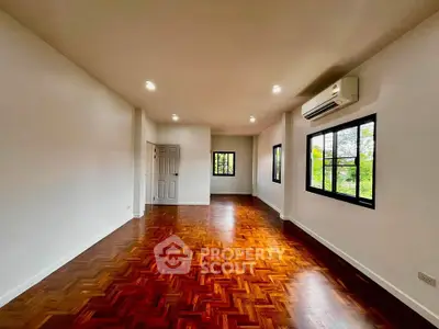 Spacious living room with elegant wooden flooring and large windows offering natural light.