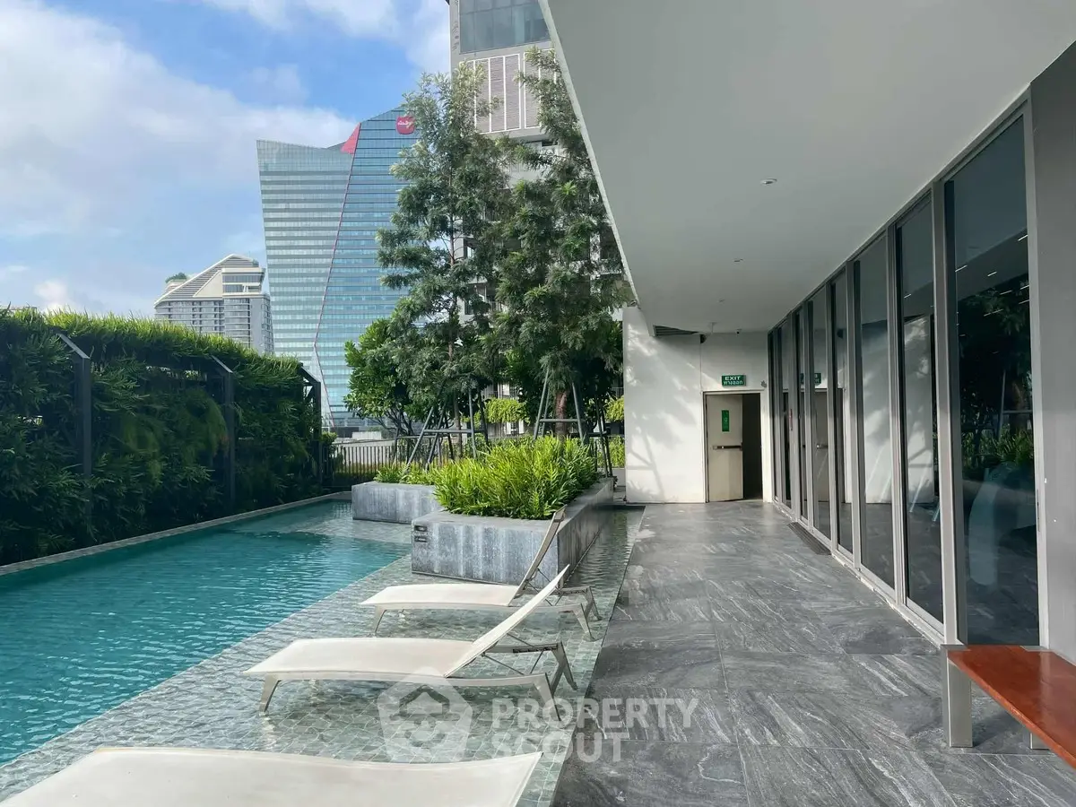 Luxurious poolside area with modern lounge chairs and lush greenery, perfect for relaxation and leisure.