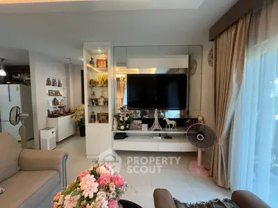 Elegant living room with modern decor, large TV, and stylish shelving in a cozy home setting.