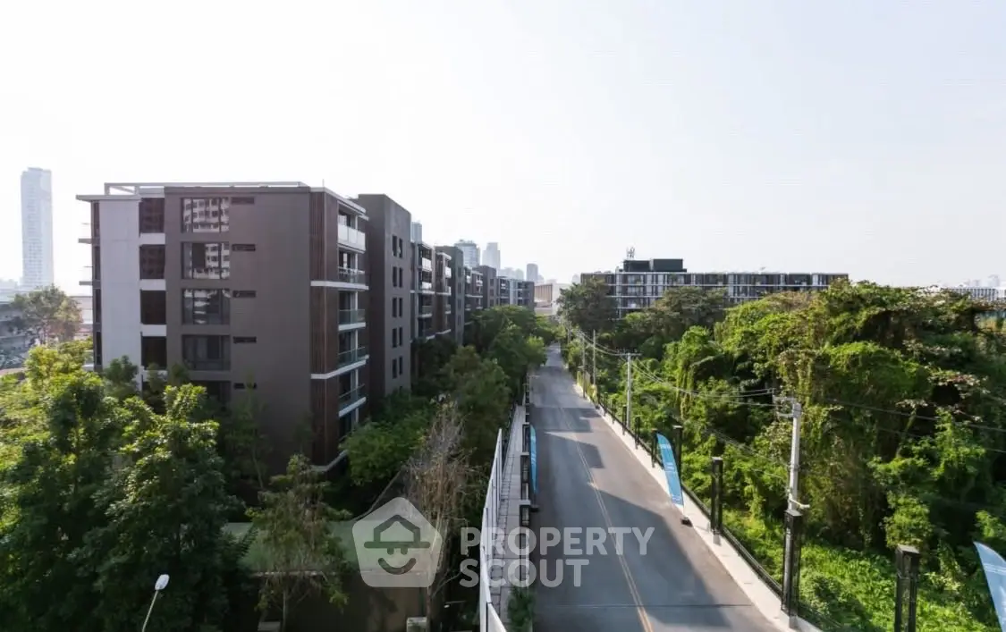 Scenic view of modern residential buildings surrounded by lush greenery and clear skies.