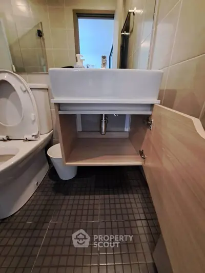Modern bathroom with sleek sink and open cabinet showcasing storage space.