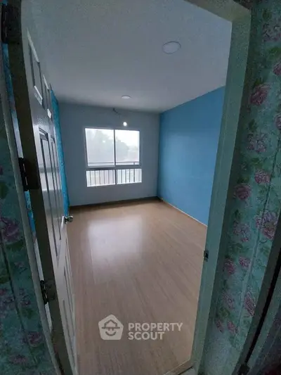 Spacious empty room with wooden flooring and blue accent wall, perfect for customization.