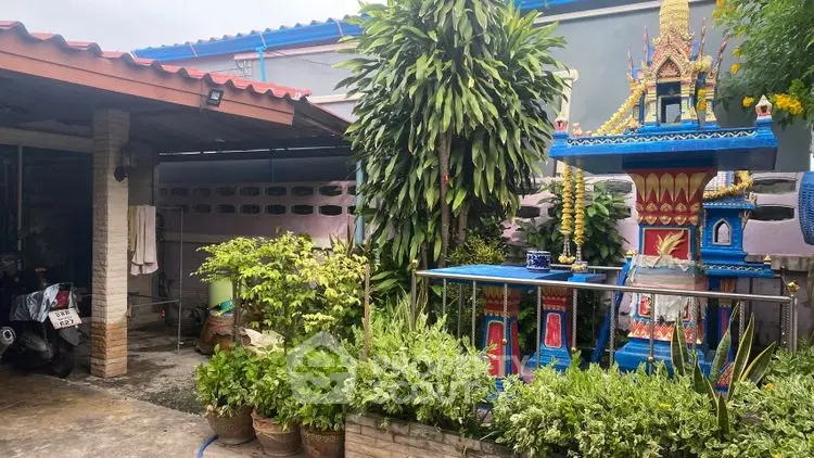 Charming garden area with vibrant spirit house and lush greenery.