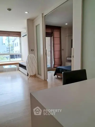 Modern open-plan living room with sliding doors leading to a cozy bedroom, featuring natural light and stylish decor.