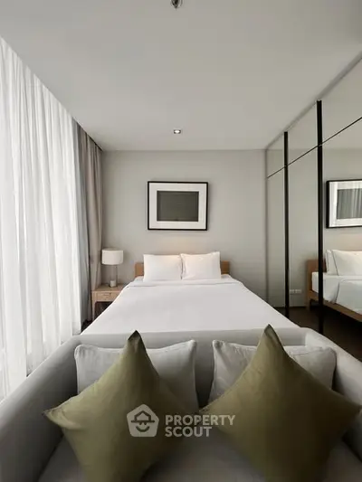 Modern bedroom with large windows and mirrored closet doors, featuring a cozy bed and stylish decor.