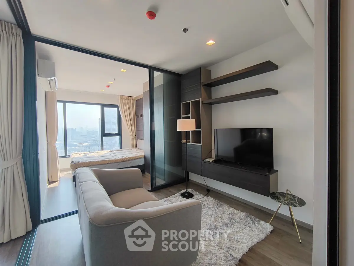 Modern living room with cozy sofa and TV, adjacent to a bright bedroom with city view.
