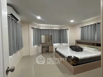 Spacious bedroom with modern furnishings and ample natural light, featuring a comfortable bed and stylish decor.