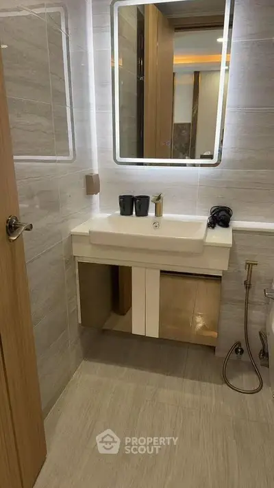 Modern bathroom with sleek vanity and illuminated mirror in stylish apartment.