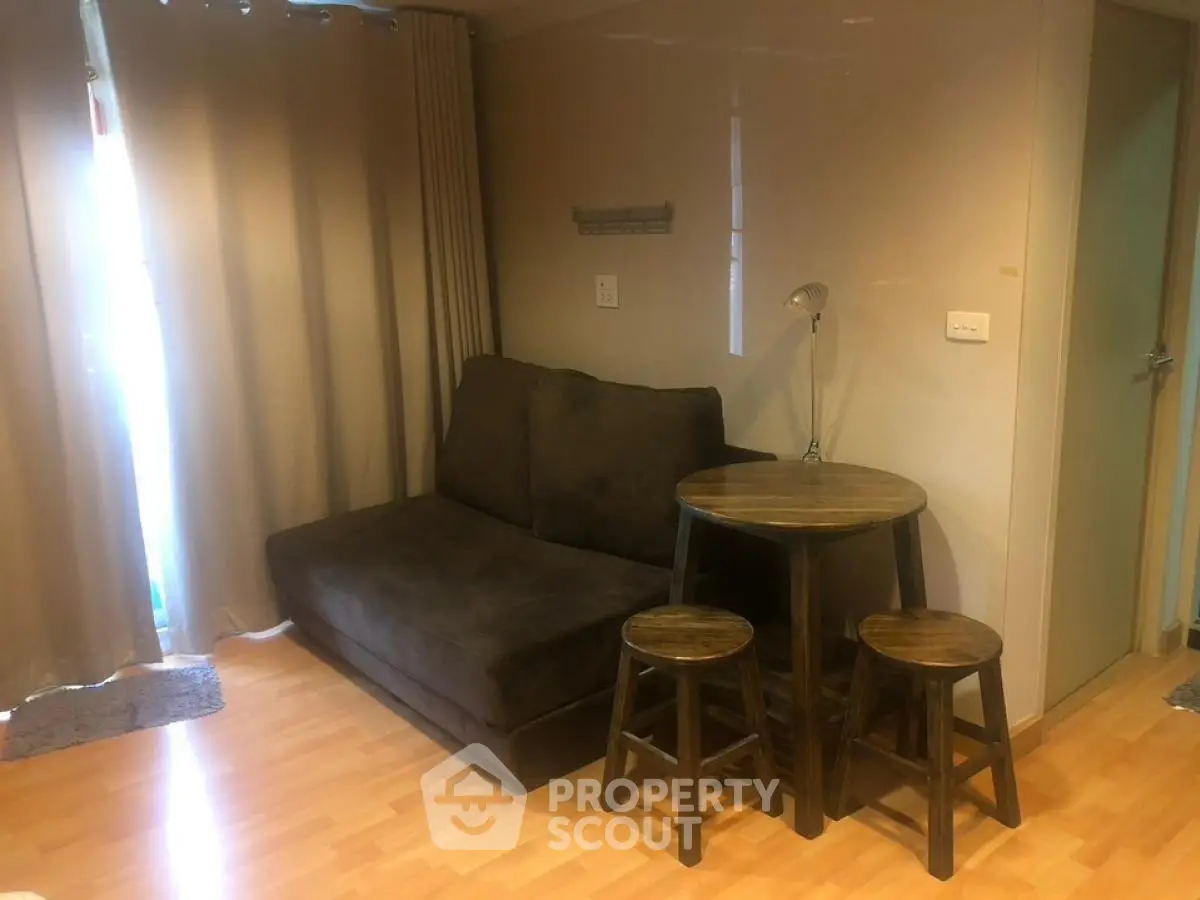 Cozy living room with dark sofa and wooden table set, perfect for small apartments.