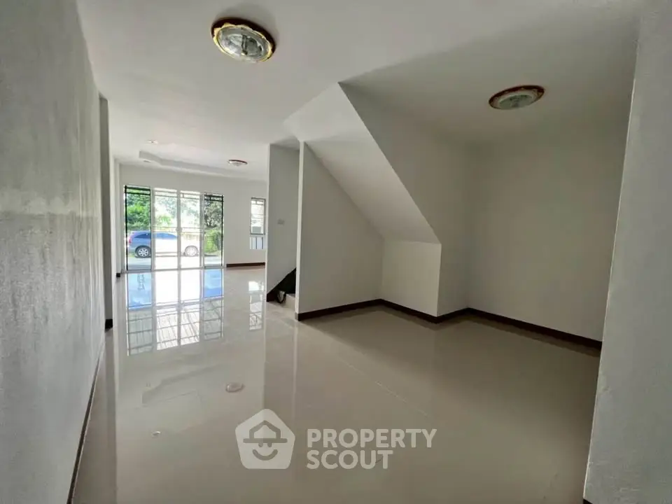 Spacious living area with glossy floors and natural light, ideal for modern living.