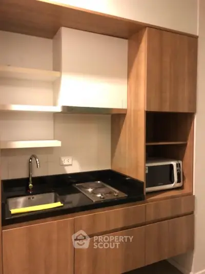 Modern kitchen with wooden cabinets and built-in microwave in a compact layout.