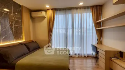 Modern bedroom with large window, stylish decor, and workspace in a cozy apartment.