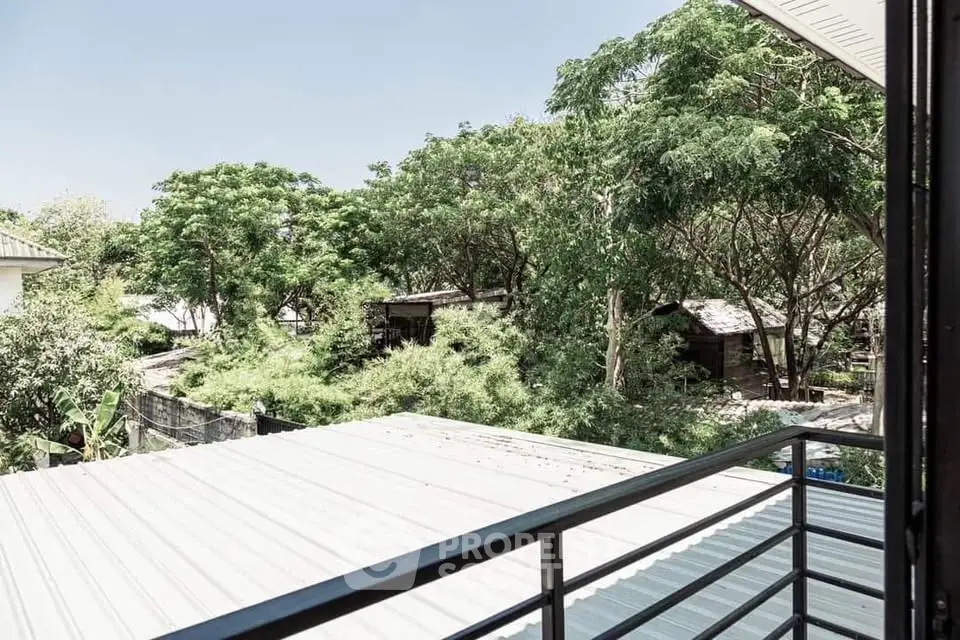 Charming balcony view overlooking lush greenery and rooftops, perfect for nature lovers.