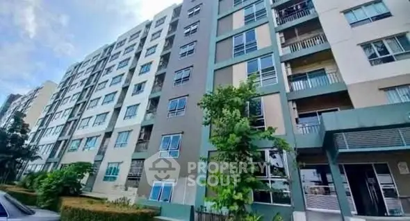 Modern multi-story apartment building with lush greenery and spacious balconies.