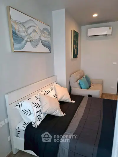 Modern bedroom with stylish decor and air conditioning, featuring a cozy bed and elegant artwork.