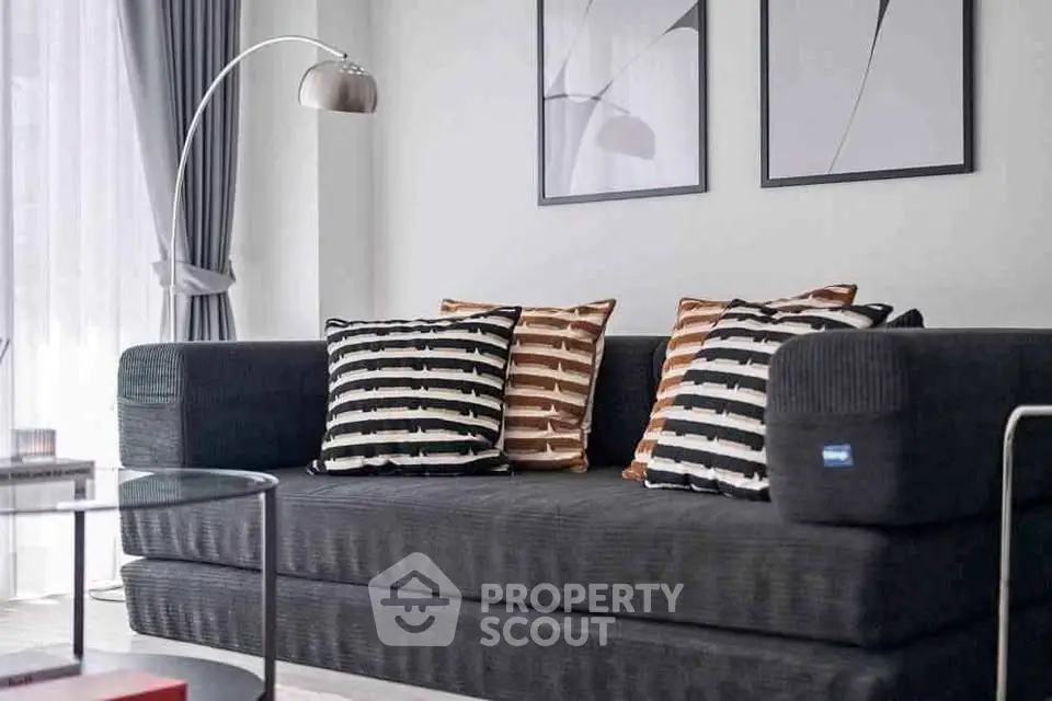 Modern living room with stylish black sofa and striped cushions, complemented by elegant decor and natural light.