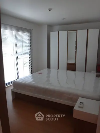 Modern bedroom with large window and sleek wardrobe in a stylish apartment.
