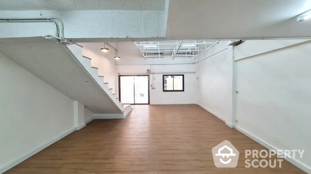 Spacious multi-level open floor plan interior with hardwood floors, industrial-style ceiling, and ample natural light from large windows, ideal for creative loft living.