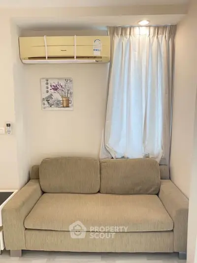 Cozy living room with beige sofa and air conditioning unit, perfect for relaxation.
