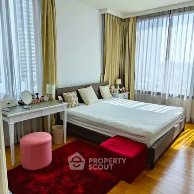 Spacious bedroom with large windows and elegant decor in a modern apartment.