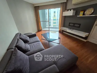 Modern living room with stylish gray sofa and glass coffee table, featuring a balcony view.