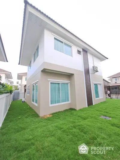 Modern two-story house with lush green lawn and contemporary design