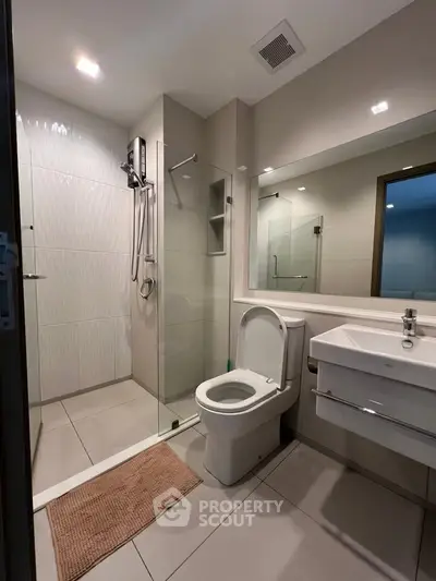 Modern bathroom with glass shower and sleek fixtures in contemporary apartment.