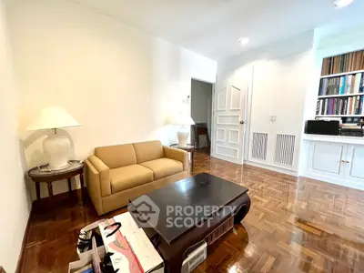 Charming living room with parquet flooring, cozy sofa, and built-in bookshelves for a warm ambiance.