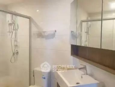Modern bathroom with shower, toilet, and sleek vanity mirror.
