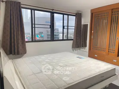 Spacious bedroom with large window and wooden wardrobe in modern apartment