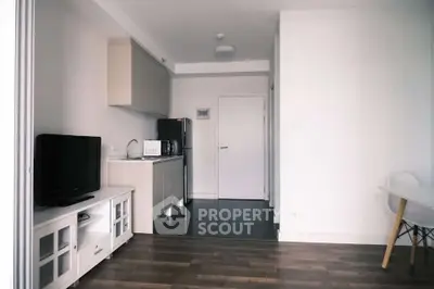 Modern apartment interior with compact kitchen and living area, featuring sleek appliances and minimalist design.