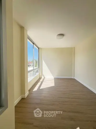 Bright and spacious empty room with large windows and wooden flooring, perfect for customization.