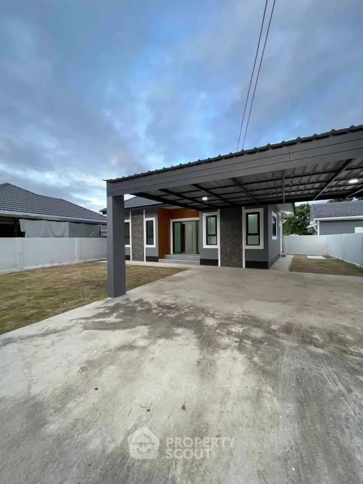 Modern single-story house with spacious driveway and carport in a suburban neighborhood.