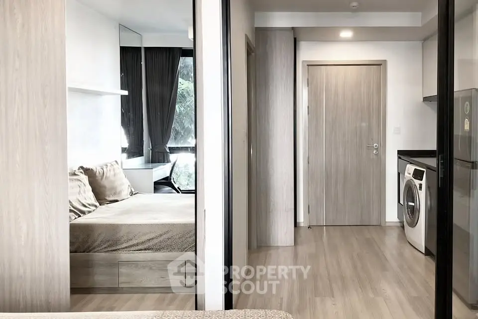 Modern apartment interior with bedroom and kitchen featuring washing machine and sleek design.