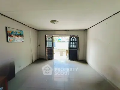 Spacious living room with open doors leading to a bright outdoor area.
