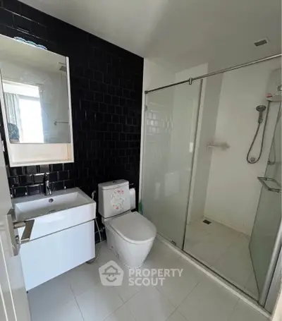 Modern bathroom with sleek black tile wall and glass shower enclosure