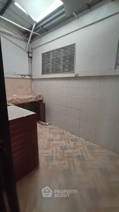Spacious utility area with tiled flooring and ample natural light, perfect for laundry or storage needs.