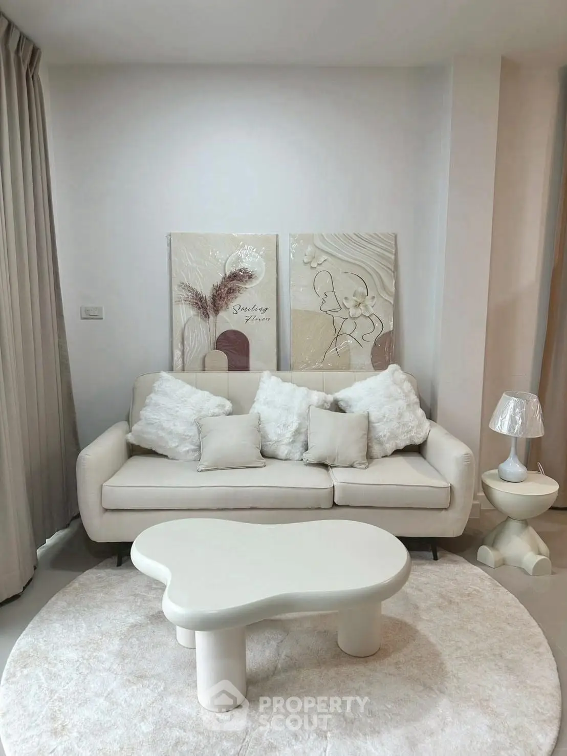 Elegant living room with modern white sofa, abstract art, and unique coffee table.