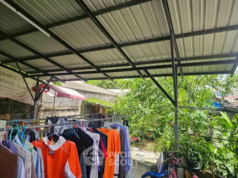Spacious outdoor laundry area with metal roof and lush greenery