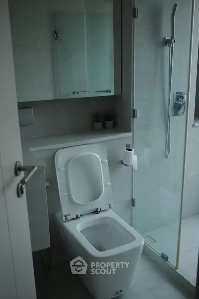 Modern bathroom with glass shower and sleek fixtures in contemporary apartment.