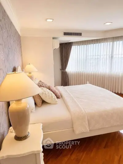 Elegant bedroom with large windows and stylish decor, featuring a cozy bed and soft lighting.