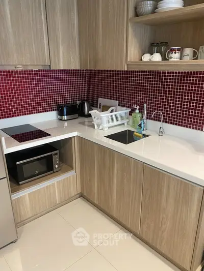 Modern kitchen with sleek cabinetry and red tile backsplash, featuring built-in appliances and stylish countertops.