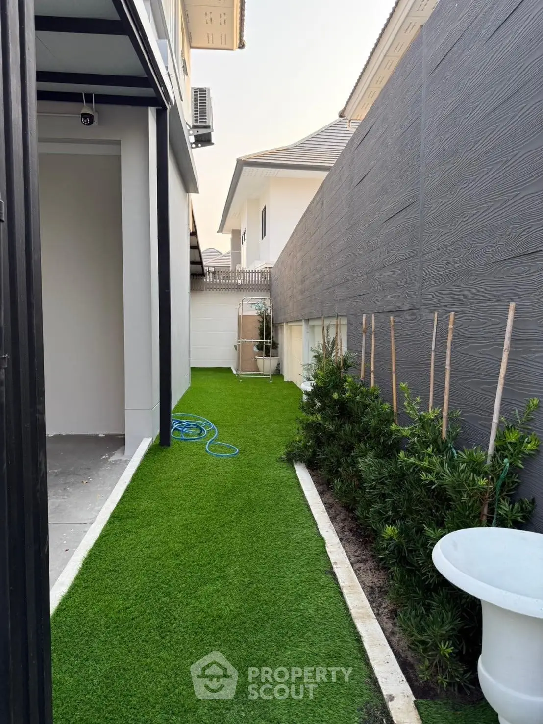 Charming narrow garden with artificial grass and modern exterior design, perfect for urban living.
