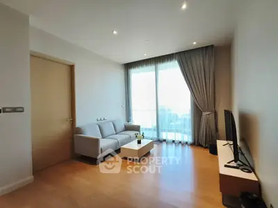 Modern living room with sleek furniture and large window offering natural light.