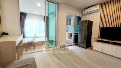 Modern open-plan living room with kitchen and dining area, featuring sleek furniture and natural light.