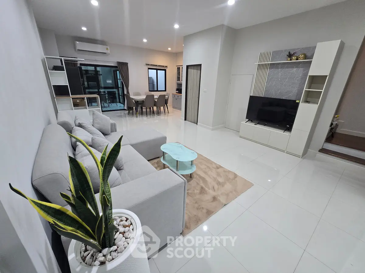 Spacious modern living room with sleek design and open layout, featuring a cozy gray sofa and stylish decor.